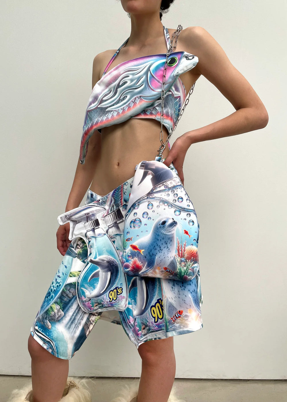 Person wearing a colorful outfit with fish and coral design on a plain background