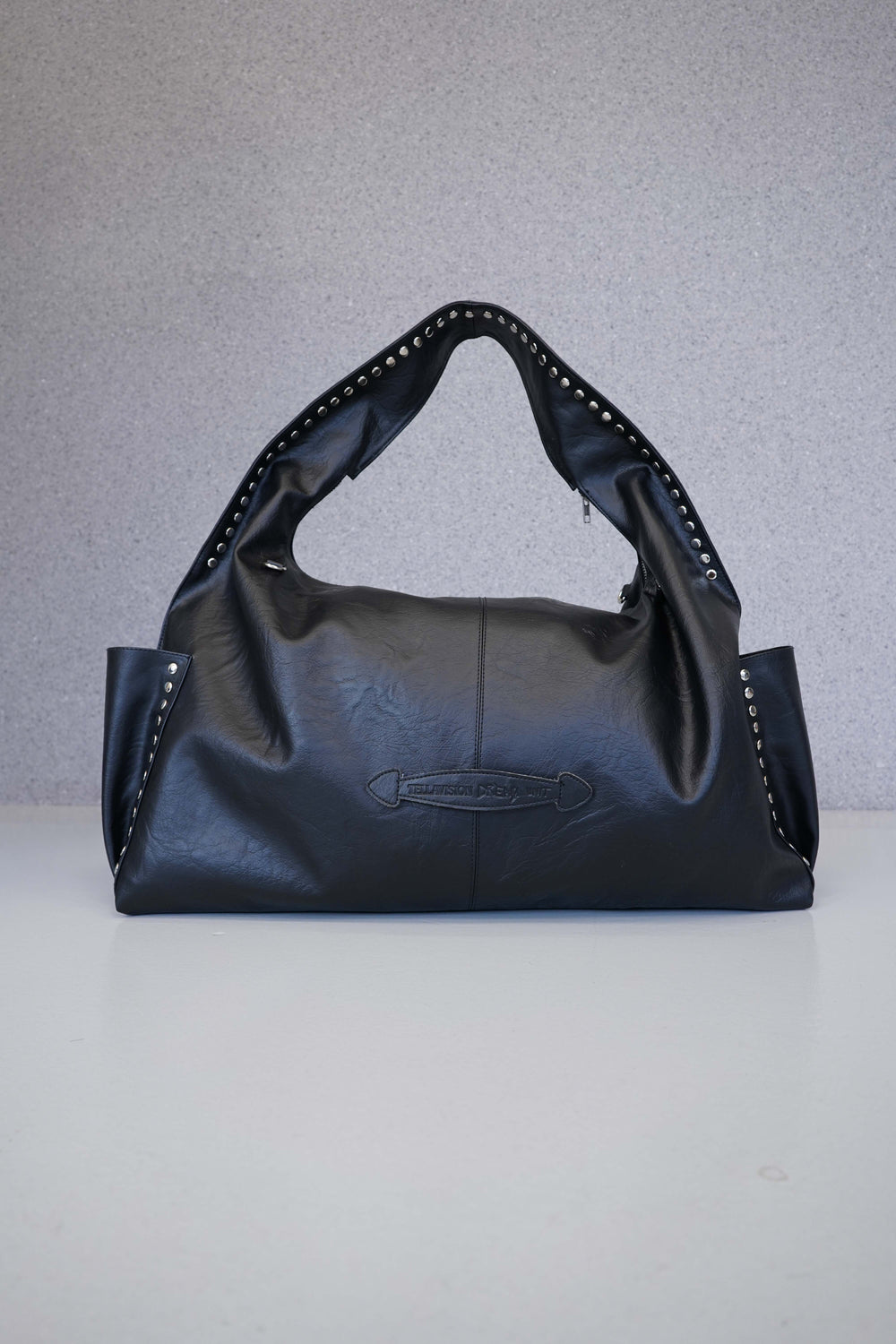 Black leather handbag with studded details on a light gray background