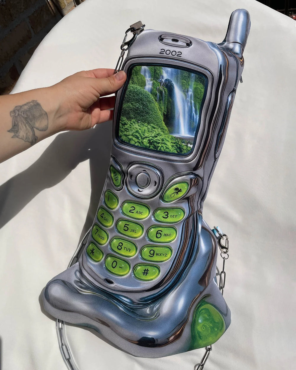 Vintage silver and green flip phone with a waterfall on the screen