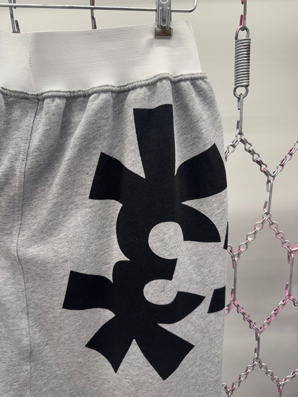 Gray sweatpants with a black symbol on a hanger against a metallic chain background