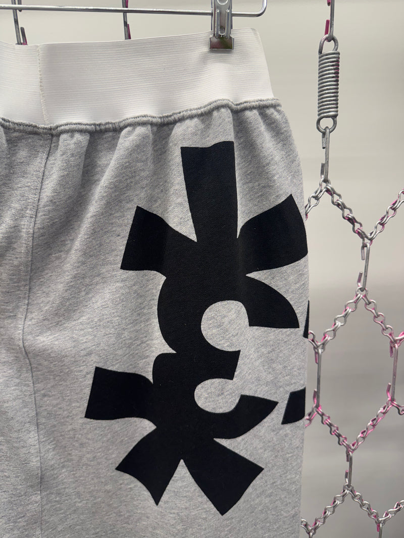 Gray sweatpants with a black symbol on a hanger against a metallic chain background