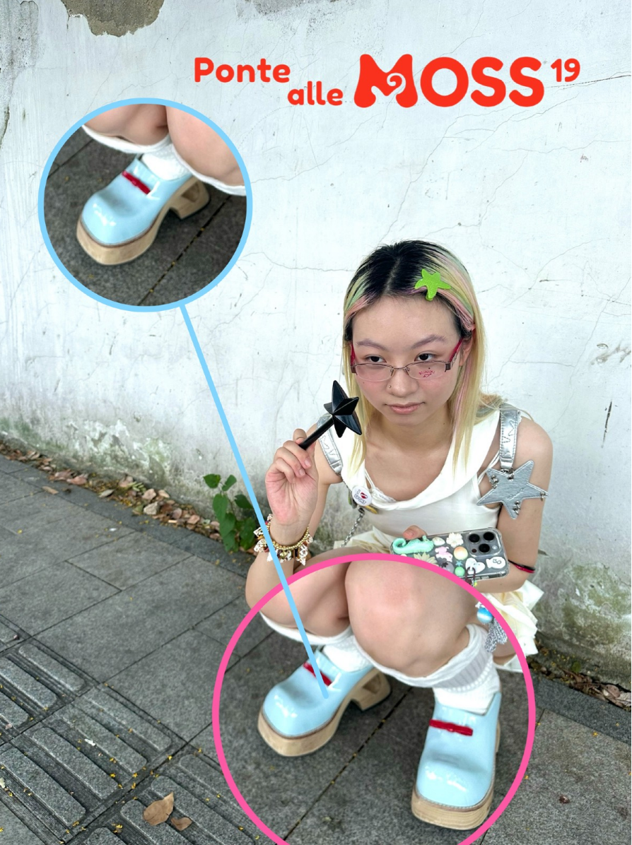 A young person crouches on a paved sidewalk, wearing a playful outfit featuring a white dress adorned with star-shaped details, pink glasses, and colorful accessories. Their hair has blonde and pastel highlights, with a green star hair clip. They hold a black star-shaped wand in one hand and a phone with a decorated case in the other. The focus of the image is on their unique shoes: blue platform clogs with wooden soles, white socks, and red straps, highlighted in a circular zoomed-in inset. The background 