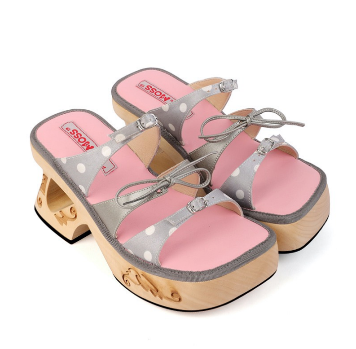 A pair of handmade wooden sandals with grey straps and polka dots, featuring a platform heel.