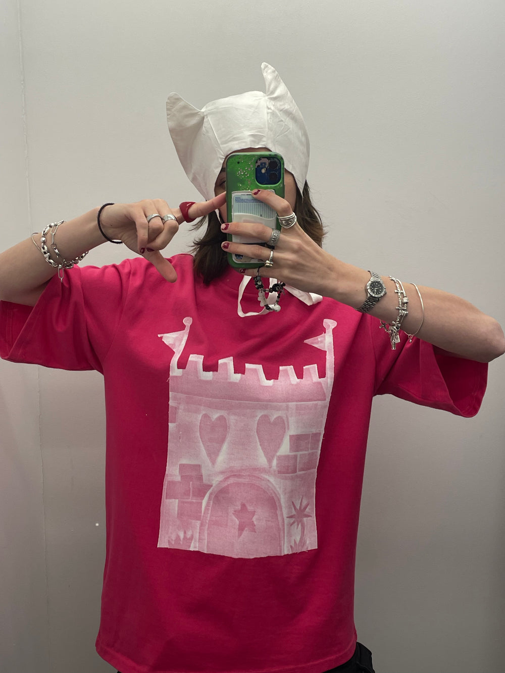 Person wearing a red t-shirt with a white graphic design, taking a mirror selfie.