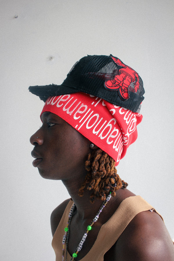 Black mesh baseball cap with red embroidered character graphic worn sideways, side view.