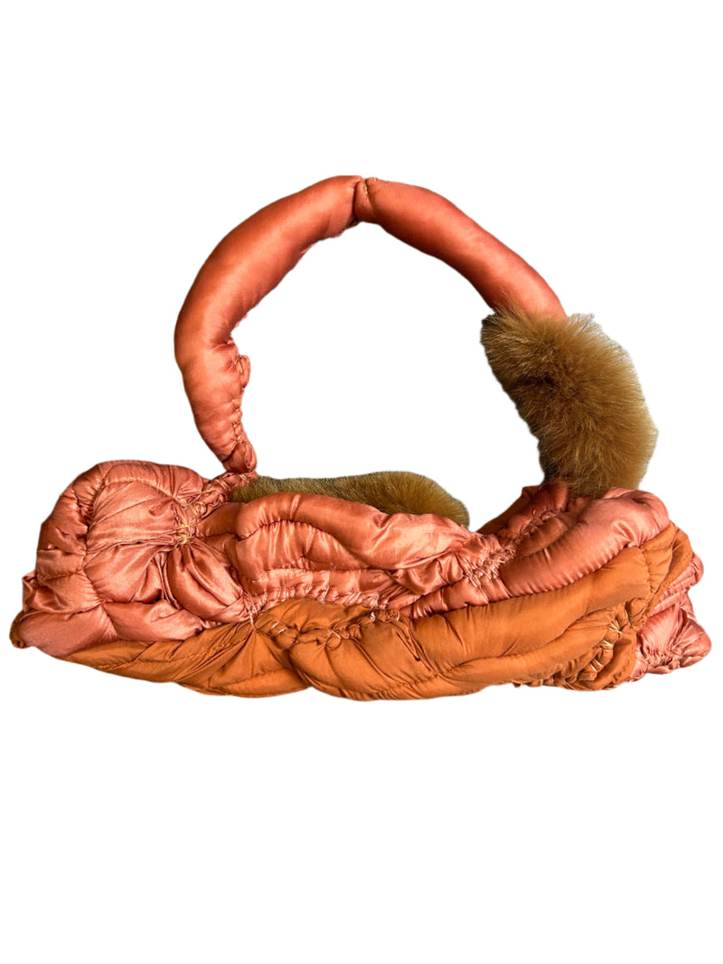 Padded pink handbag with fur on a wooden surface