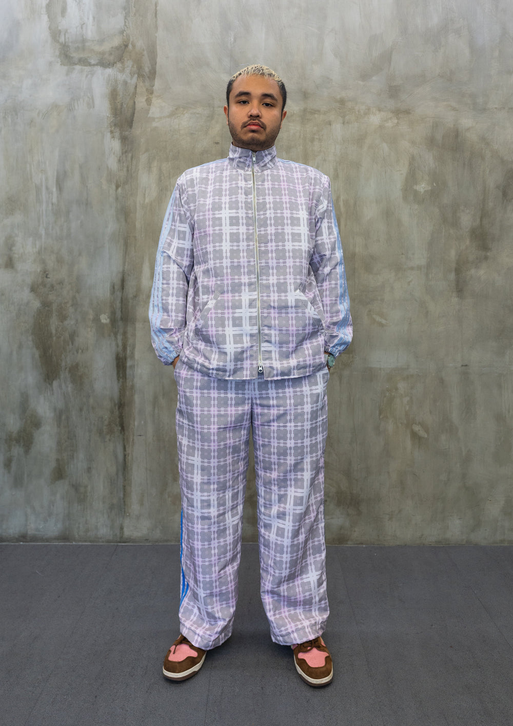 Front view of pastel tartan Tellavision jacket featuring zip-up closure, high neck collar, and relaxed fit with blue stripe sleeve detailing.
