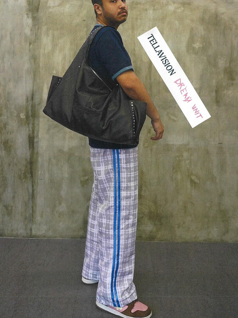 Person holding a black bag against a textured wall with a label.