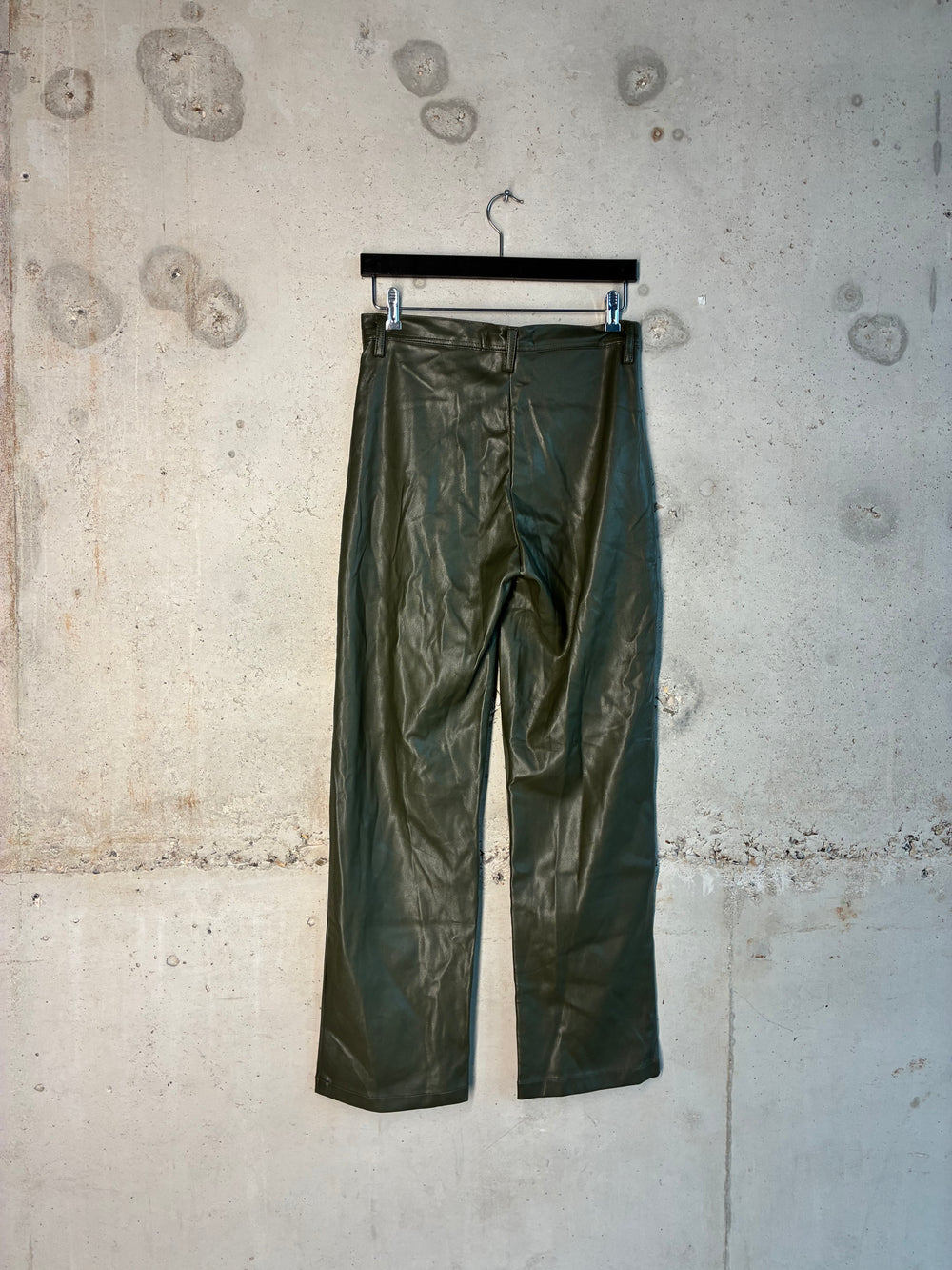 Green faux leather pants hanging on the wall. 