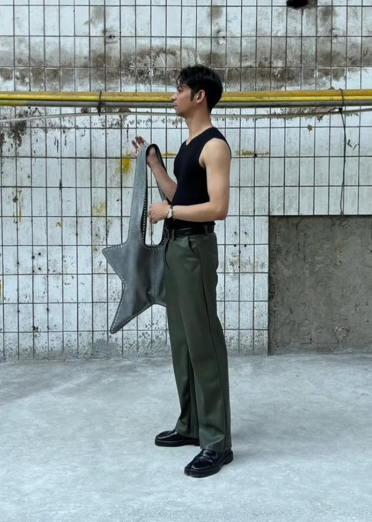 Person holding a large gray bag against a concrete wall.