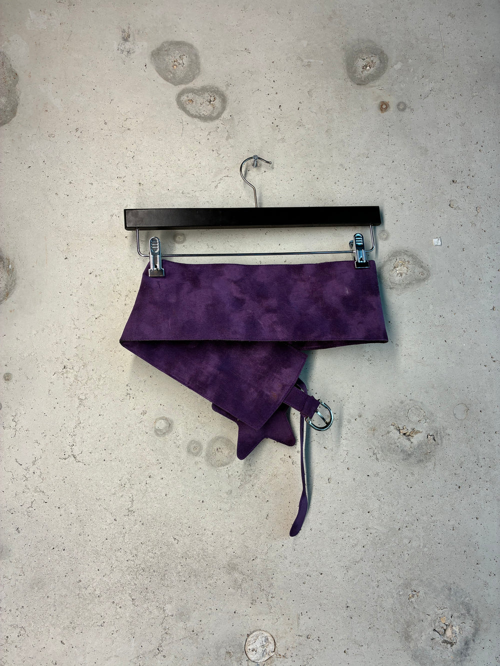 Purple fabric on a hanger against a textured gray background