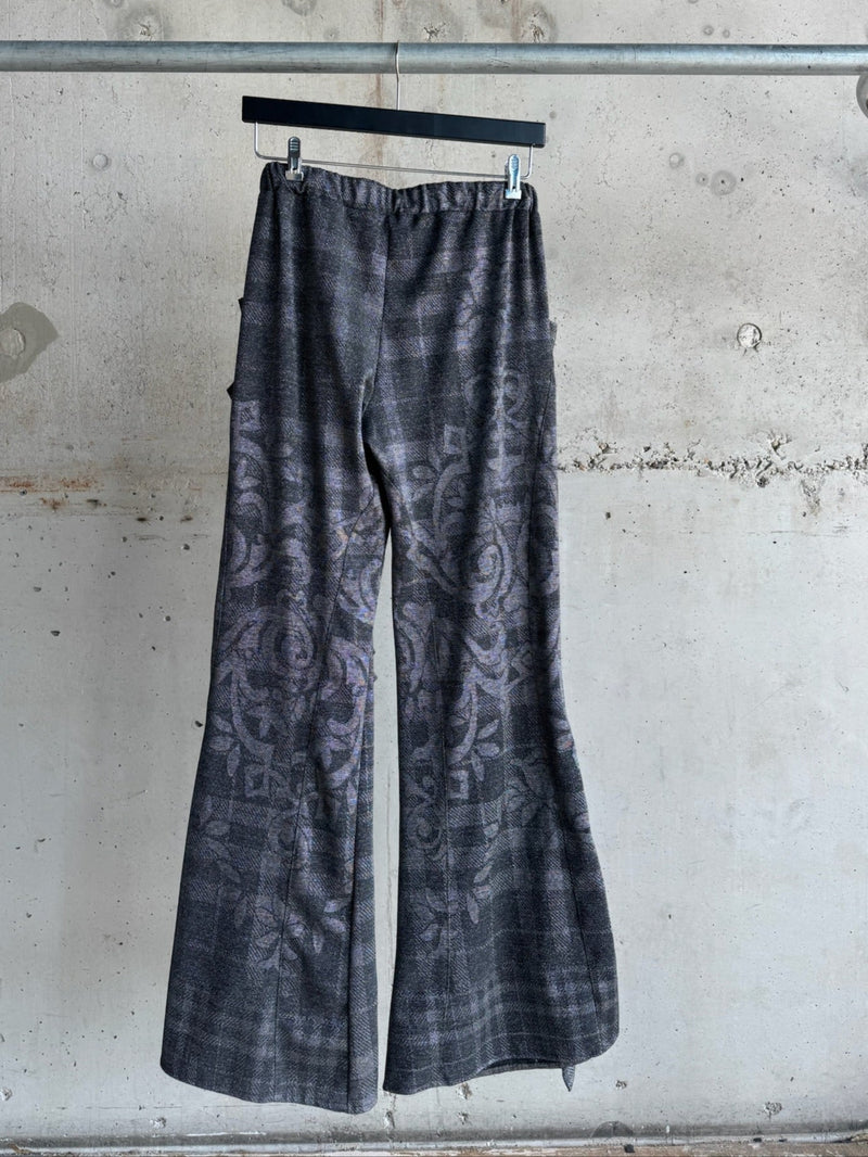 Back view of handmade charcoal grey flared pants with intricate woven floral and plaid pattern, elastic waistband, and a smooth finish – size S/M artistic statement trousers for bold, creative fashion