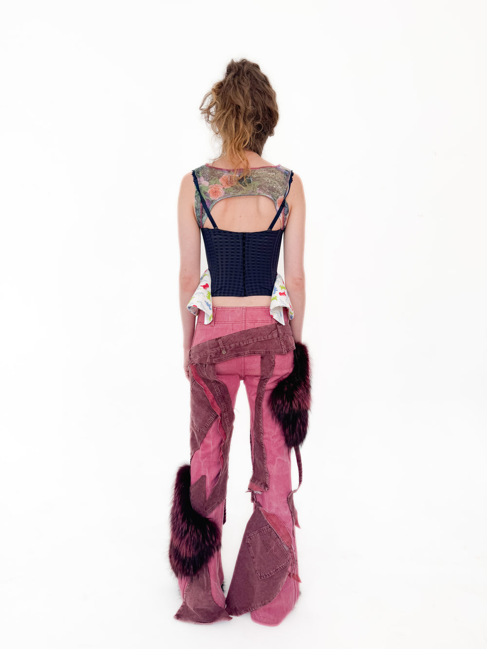 Person wearing a unique outfit with a black top and pink pants on a white background