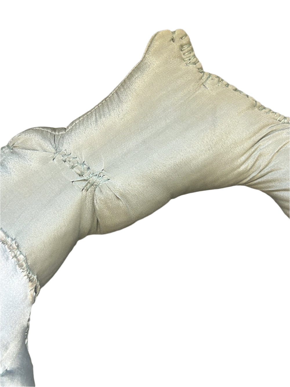 White satin bag with decorative stitching on a wooden surface