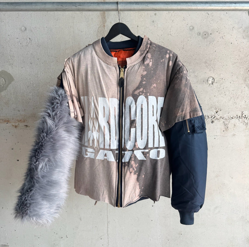 Front view of deconstructed zip-up jacket featuring bleached ‘HARDCORE GAKKO’ graphic T-shirt torso, grey faux fur left sleeve, and navy bomber-style right sleeve – unisex statement piece blending streetwear, punk, and high-fashion elements
