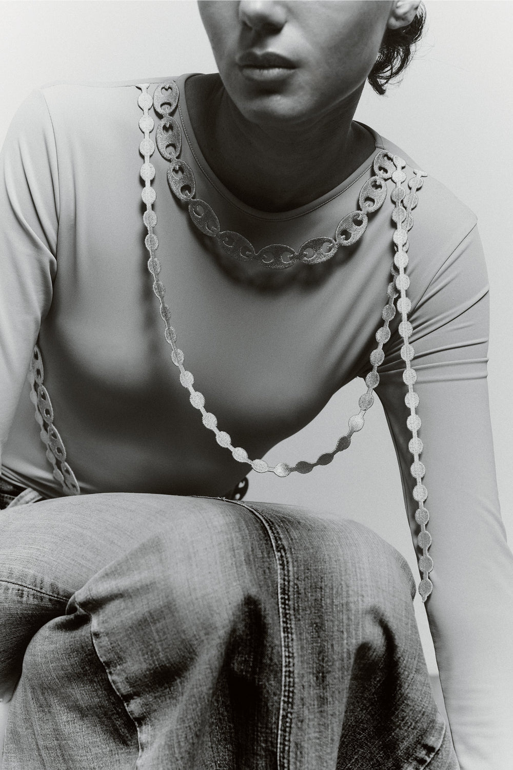 Close-up of the GYGIL Chains Body showing embroidered chain details along the neckline and sleeves on a fitted grey bodysuit.