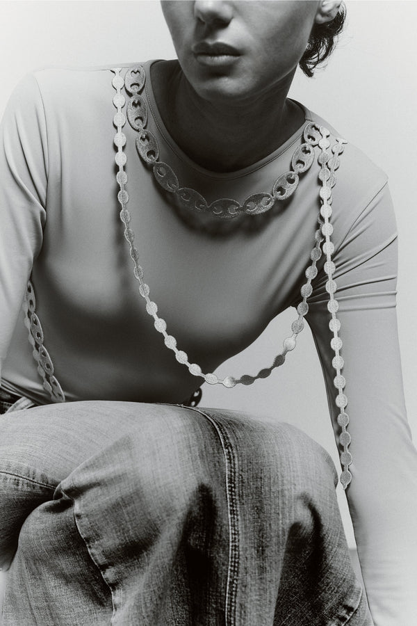 Close-up of the GYGIL Chains Body showing embroidered chain details along the neckline and sleeves on a fitted grey bodysuit.