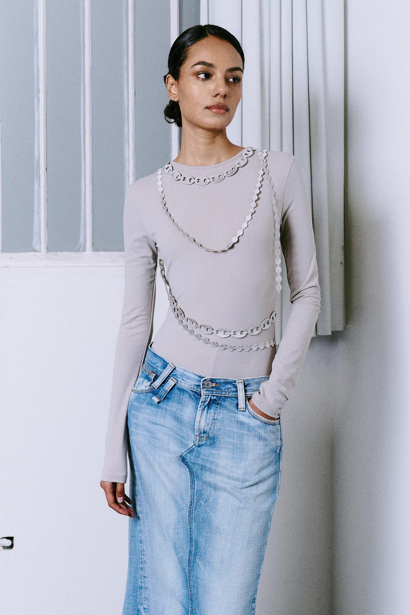 Model wearing the GYGIL Chains Body bodysuit layered with jeans, featuring all-over chain print.