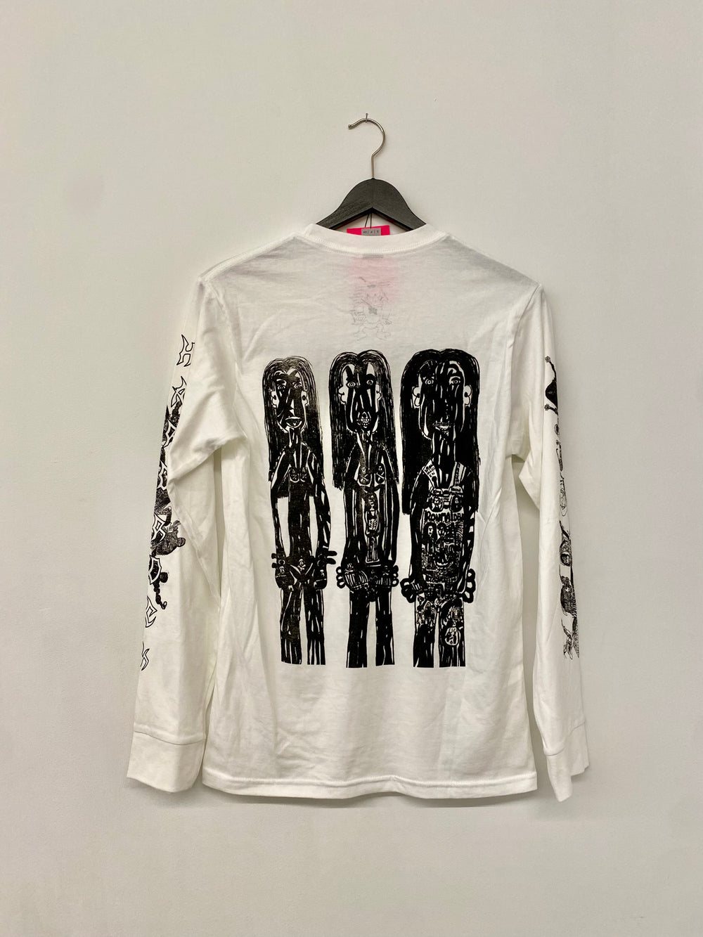 back of a white long-sleeve shirt with black  screenprinted graphic designs on a hanger 