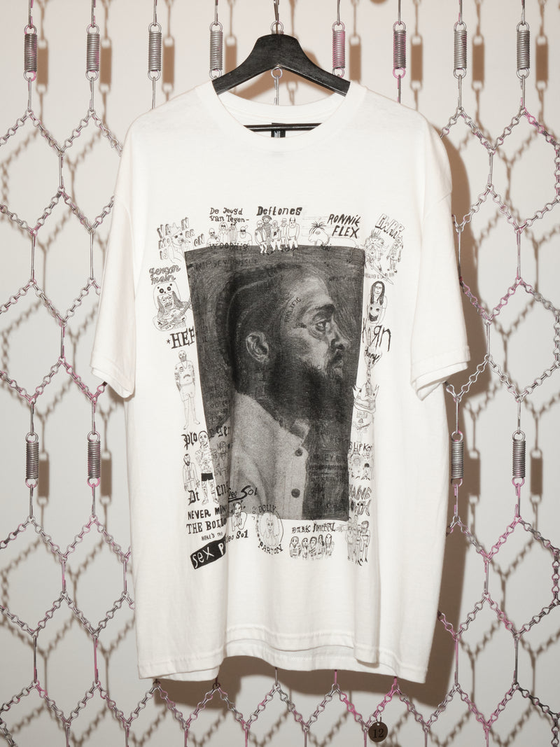 White t-shirt with graphic design on a hanger against a patterned wall.