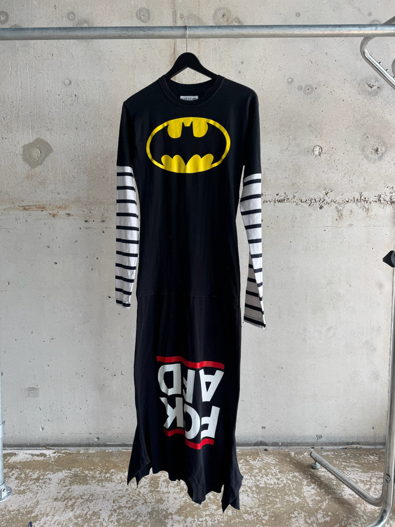 Long black dress with yellow Batman logo on the chest, striped white and black long sleeves, and bold ‘FCK ADV’ text in red and white at the bottom, featuring distressed hem and edgy streetwear style