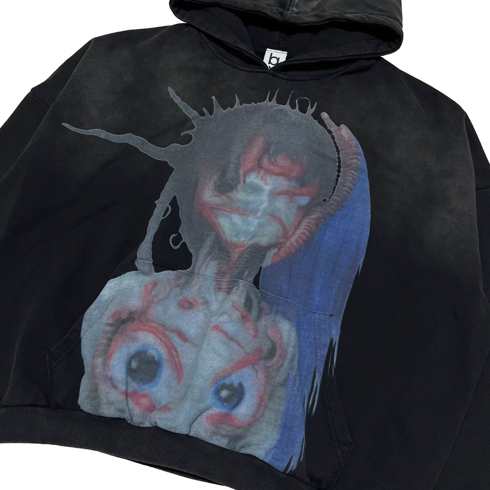 Black hoodie with a graphic design of a creature with multiple eyes and blue hair.
