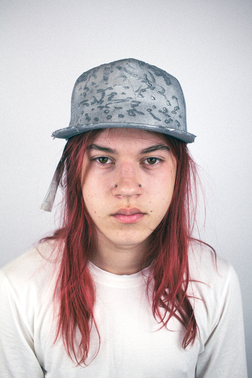 Grey distressed baseball cap worn, front view, featuring faded print texture and flat brim.