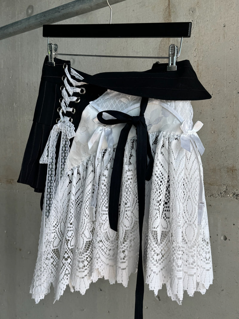 Black and white lace corset skirt featuring lace-up detailing, layered lace panels, satin ribbon ties, and asymmetrical hem, blending gothic and vintage-inspired elements in a striking streetwear design