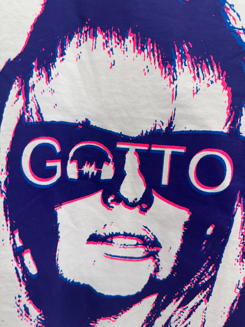 Close-up of a graphic design with a stylized face and 'Gatto' text on a blue background.