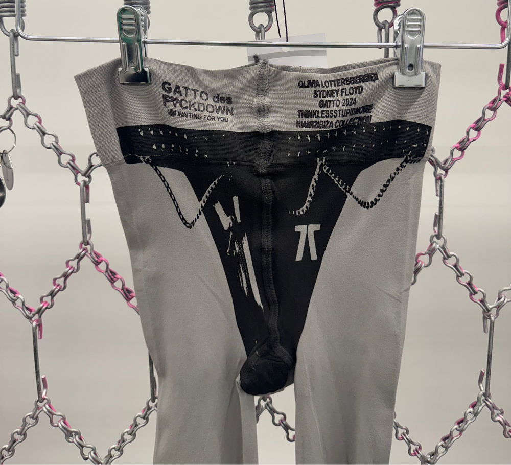 Black men's underwear with brand labels on a hanger against a chain-link fence background.