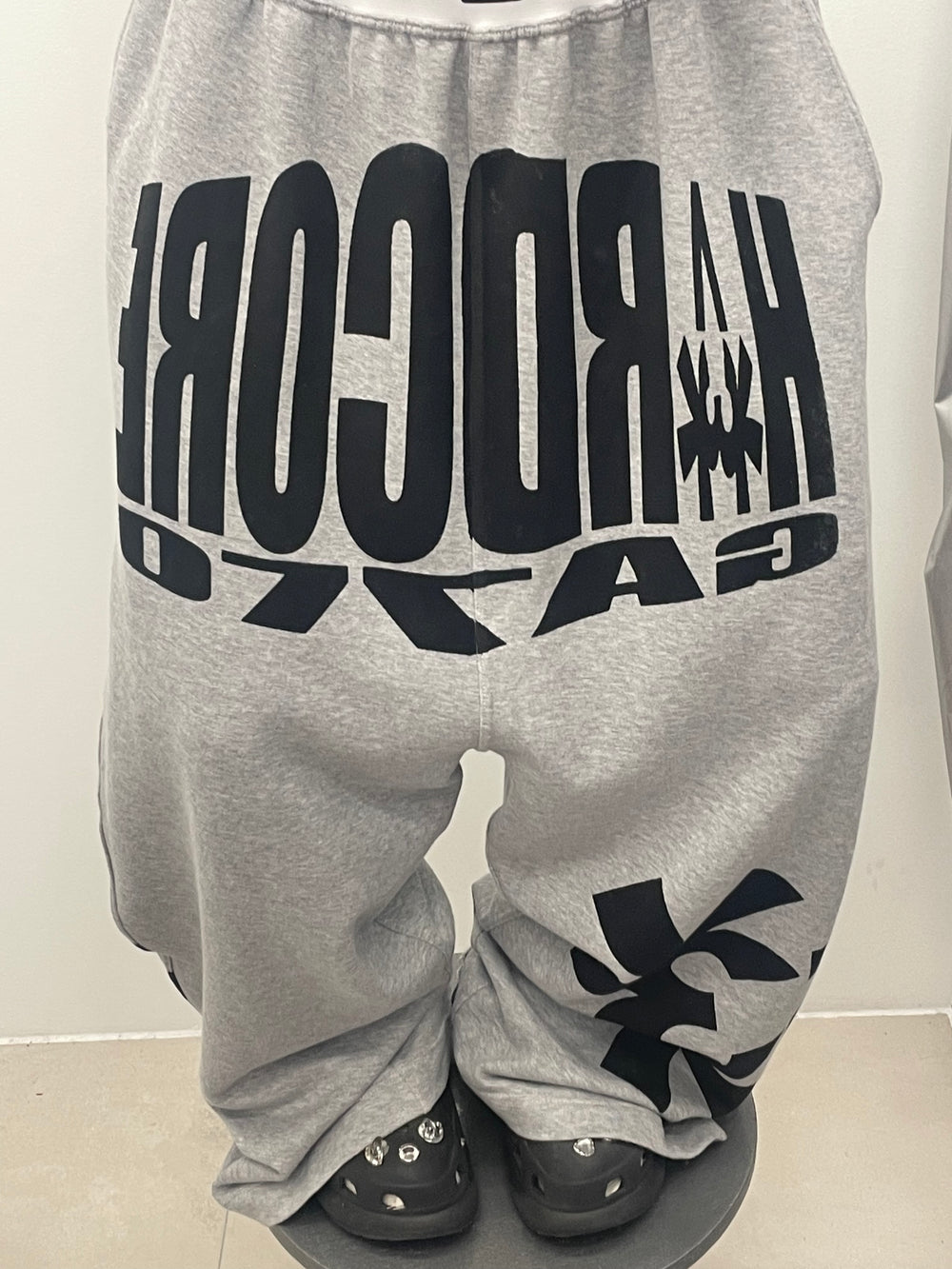 Gray sweatpants with black text and logo on a plain background