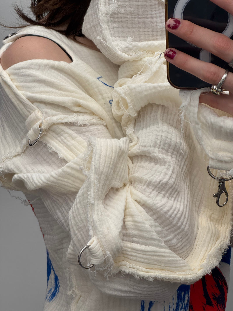 Close-up of a textured white garment with a person holding a phone.
