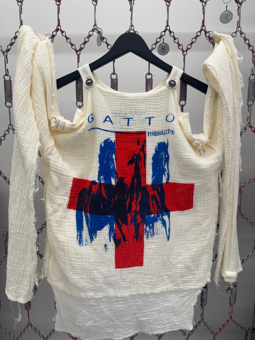 Vintage tank top with graphic design on a hanger against a textured wall.