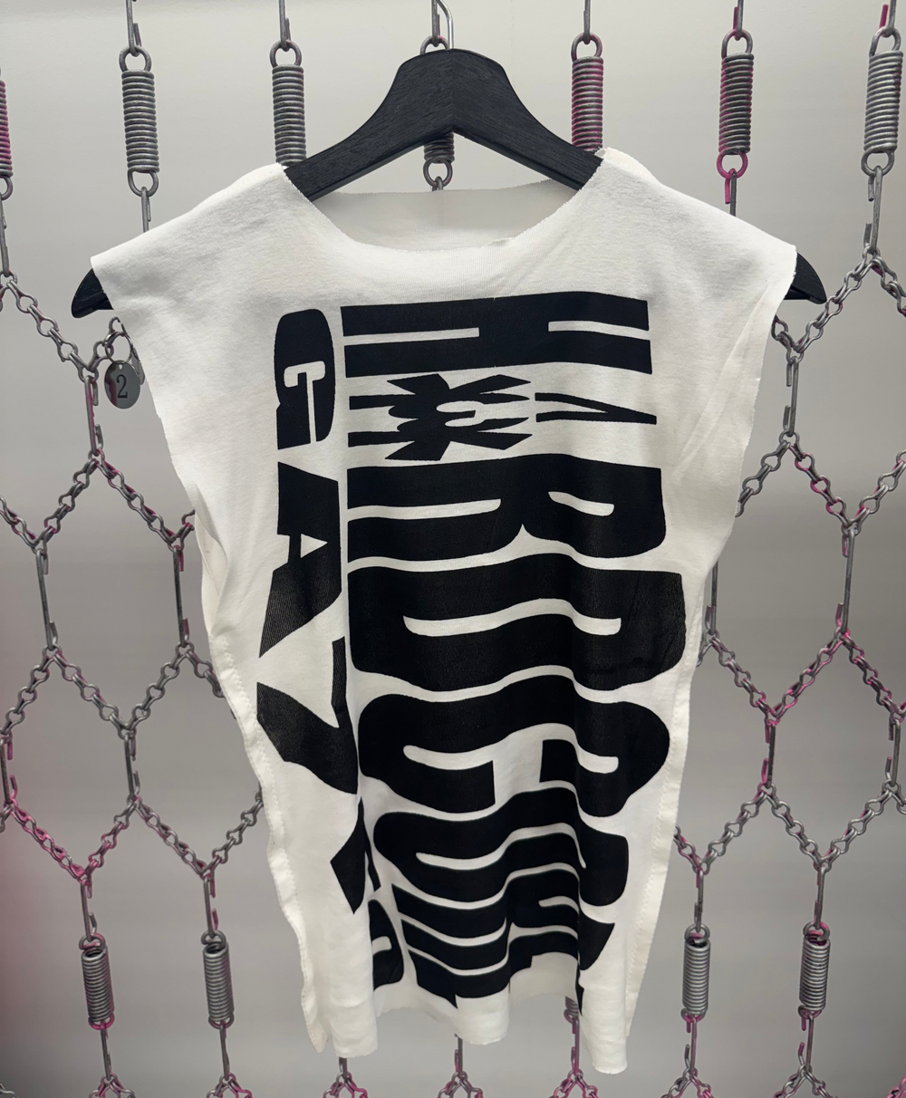White t-shirt with black graphic design on a hanger against a patterned background