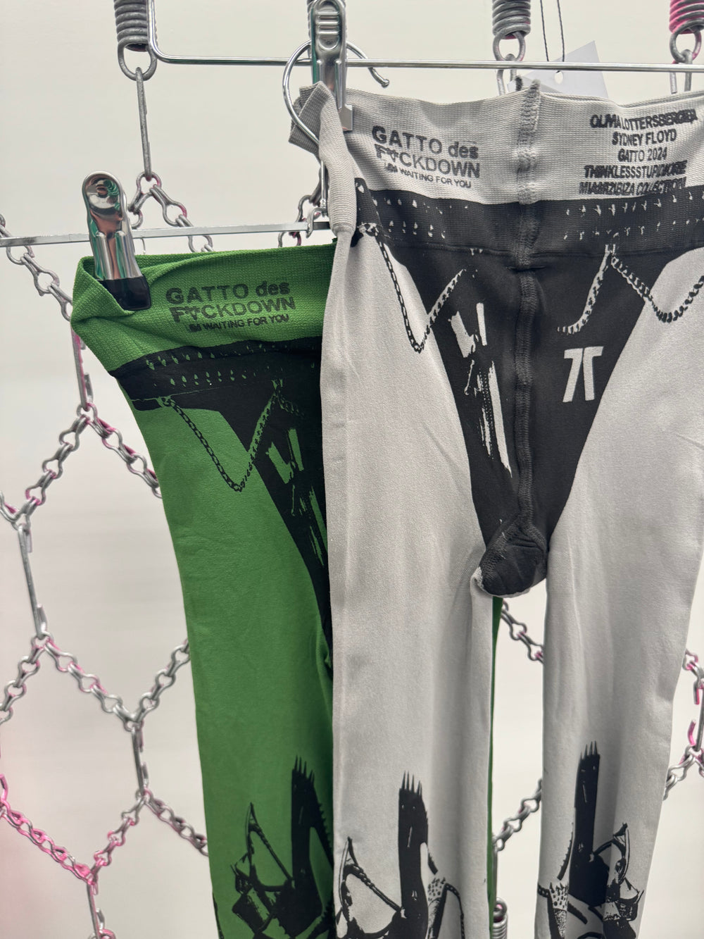 Green and gray pants with graphic designs hanging on a rack.