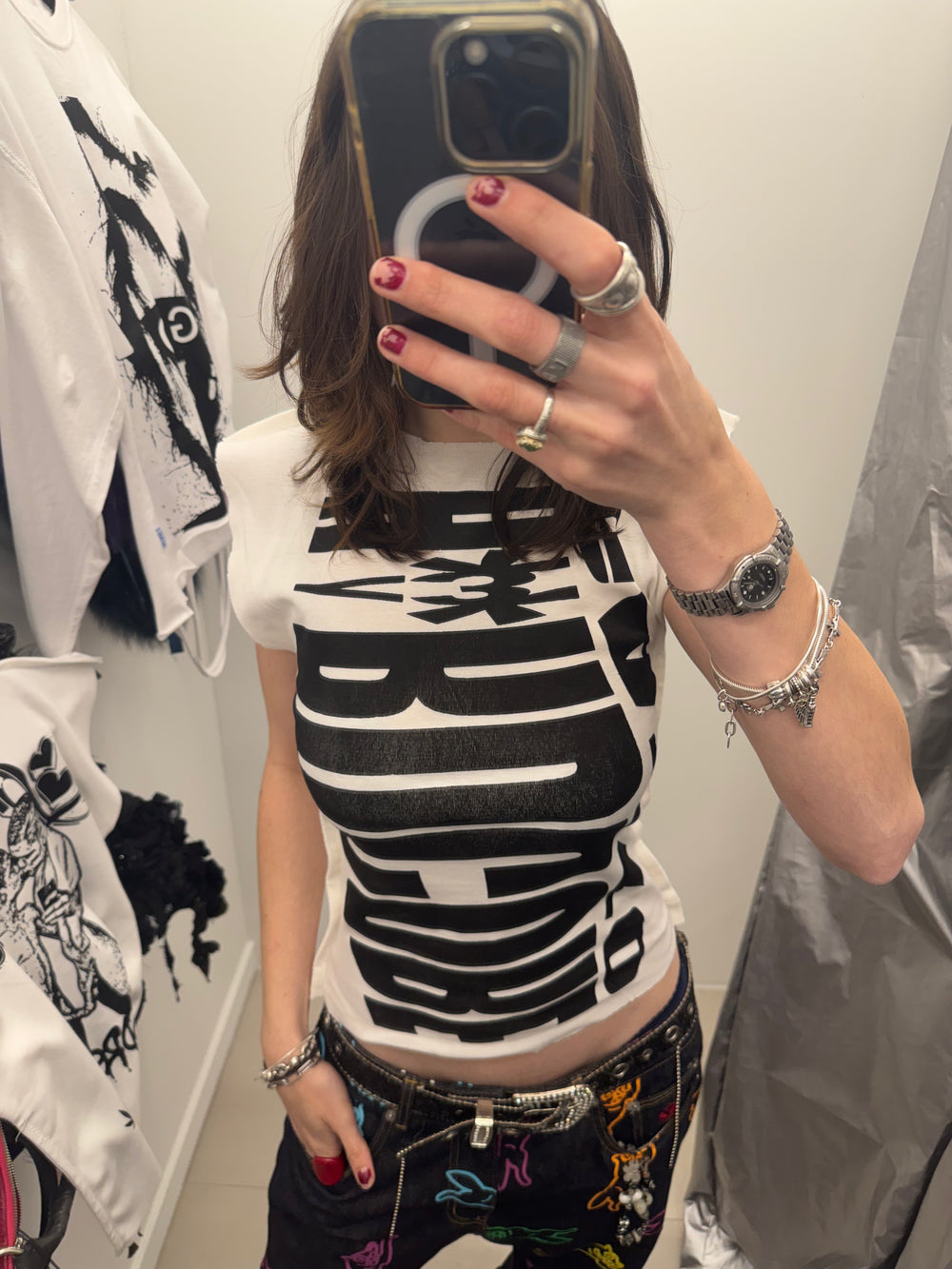 Person wearing a black and white graphic t-shirt with colorful pants in a clothing store.