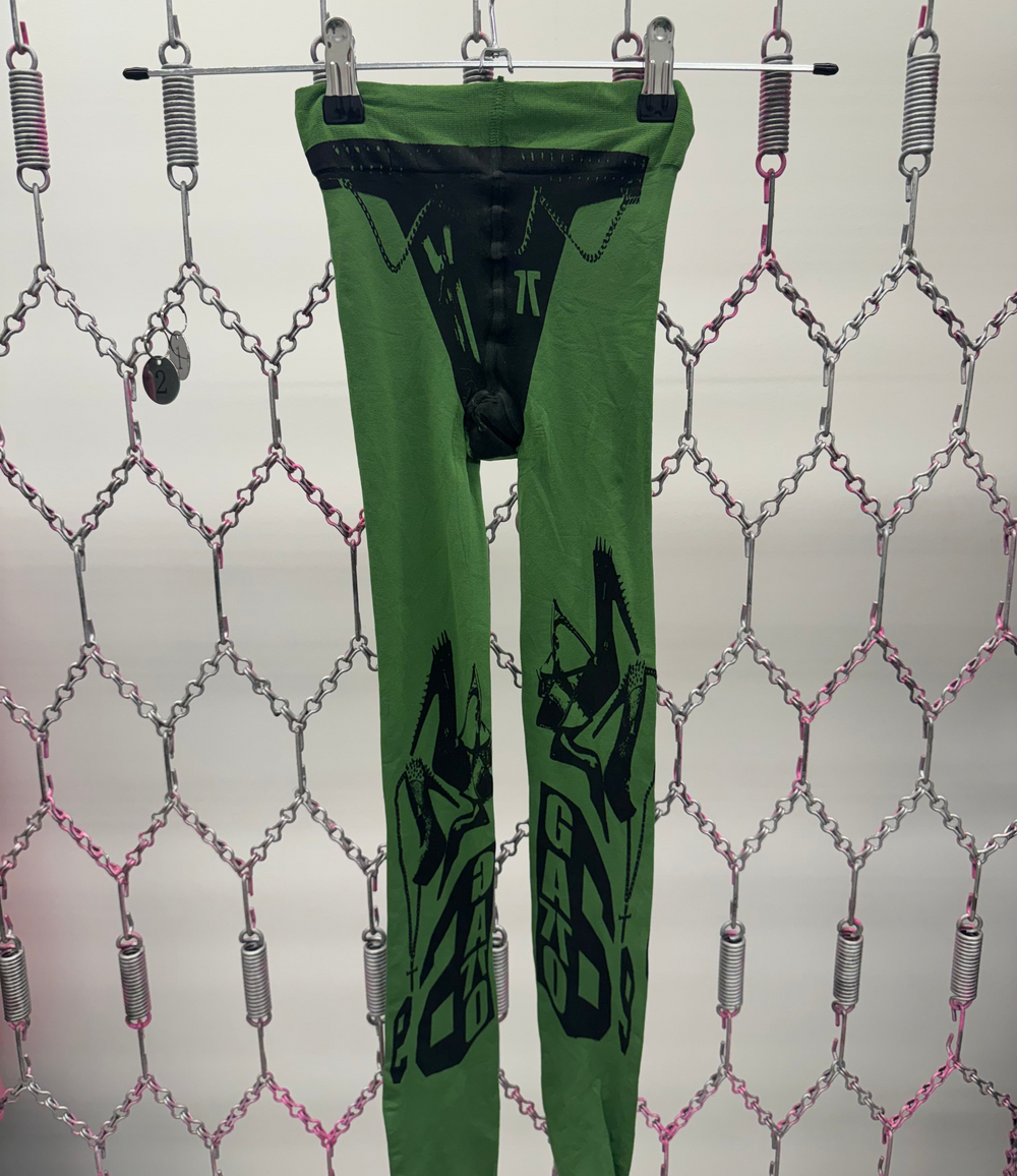 Green leggings with black designs hanging on a rack against a patterned background