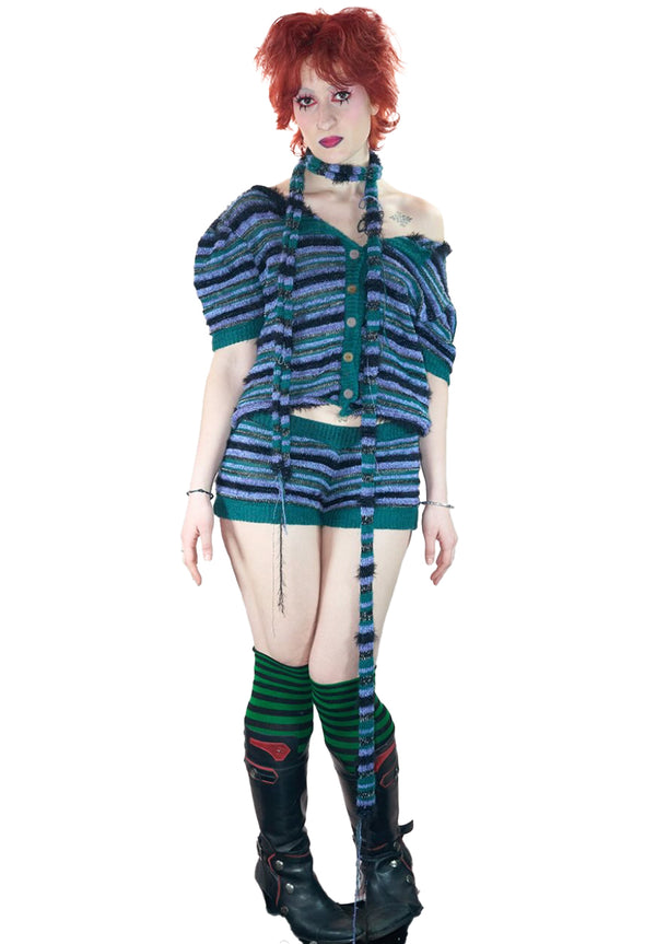 Person wearing a blue and green knitted striped outfit with a long scarf on a white background