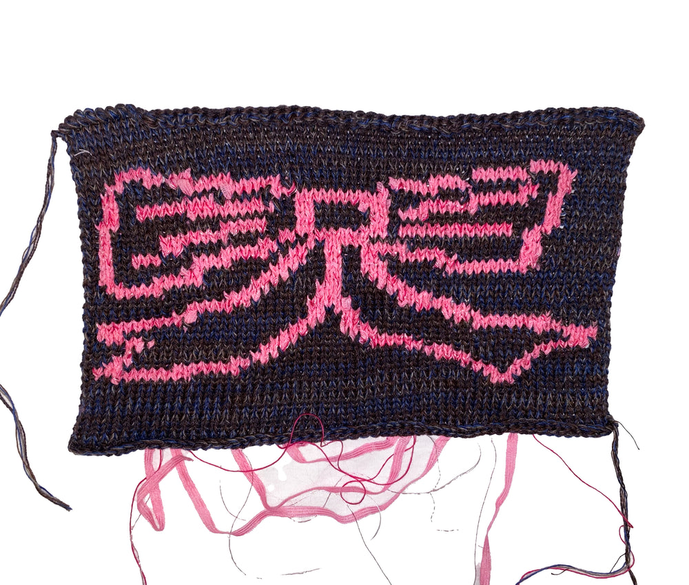 Textile piece with pink 'bow' logo on a dark background