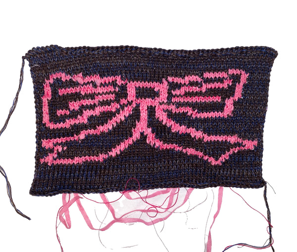 Textile piece with pink 'bow' logo on a dark background
