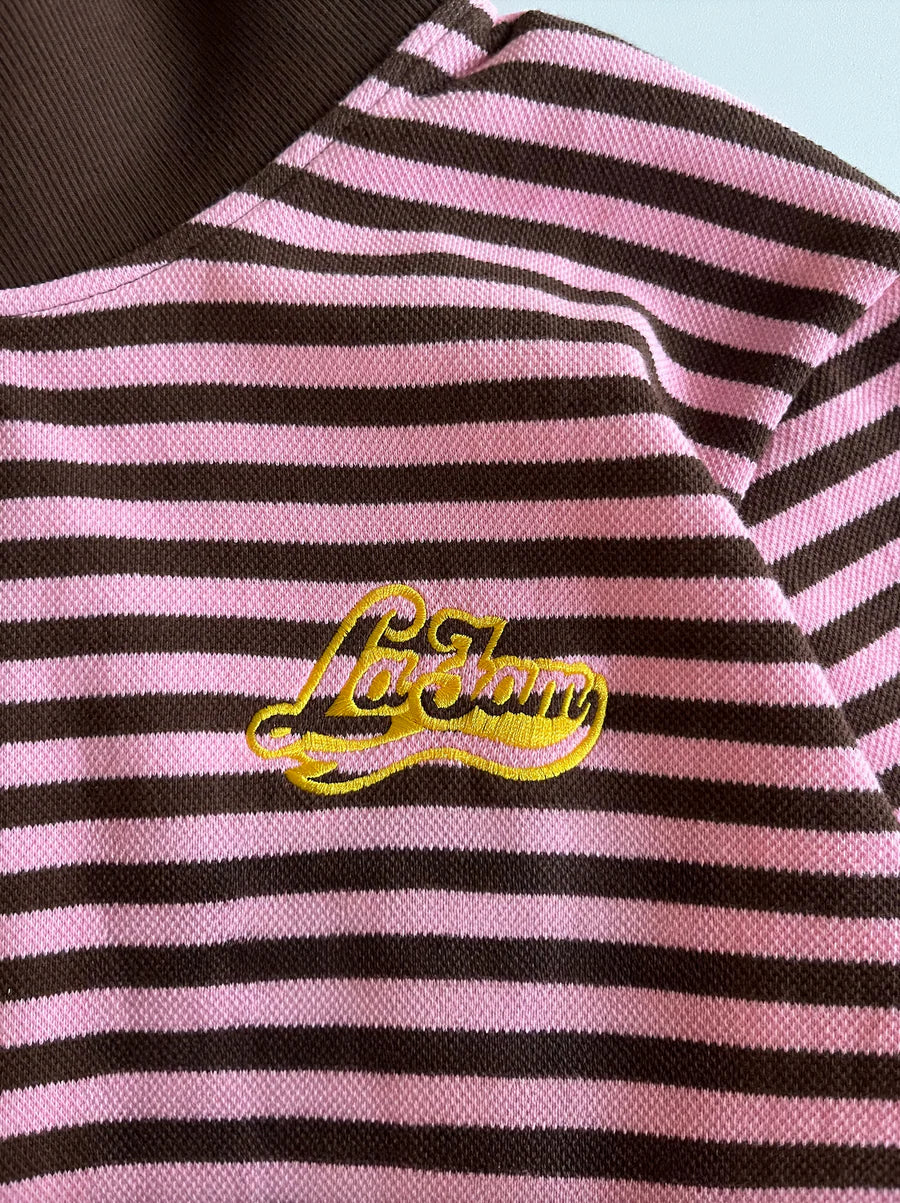 Pink and black striped shirt with a yellow logo on a light blue background
