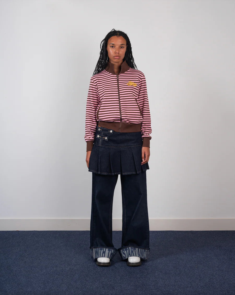 Person wearing a striped sweater and pleated skirt on a plain background