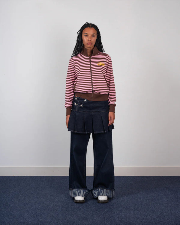 Person wearing a striped sweater and pleated skirt on a plain background