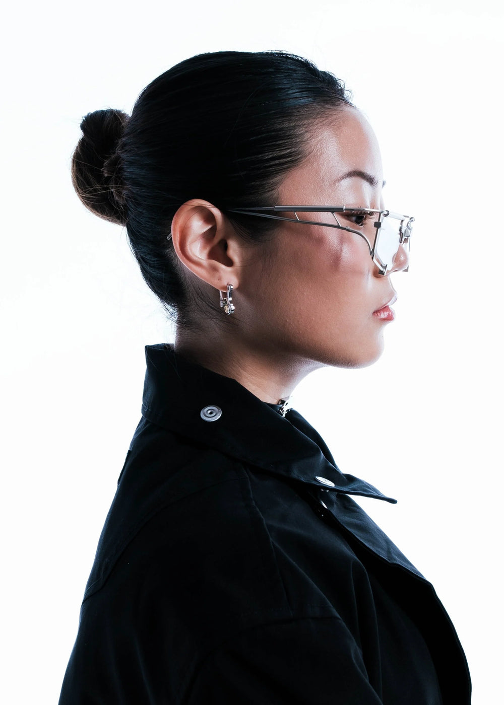 Woman wearing glasses and a black jacket on a white background