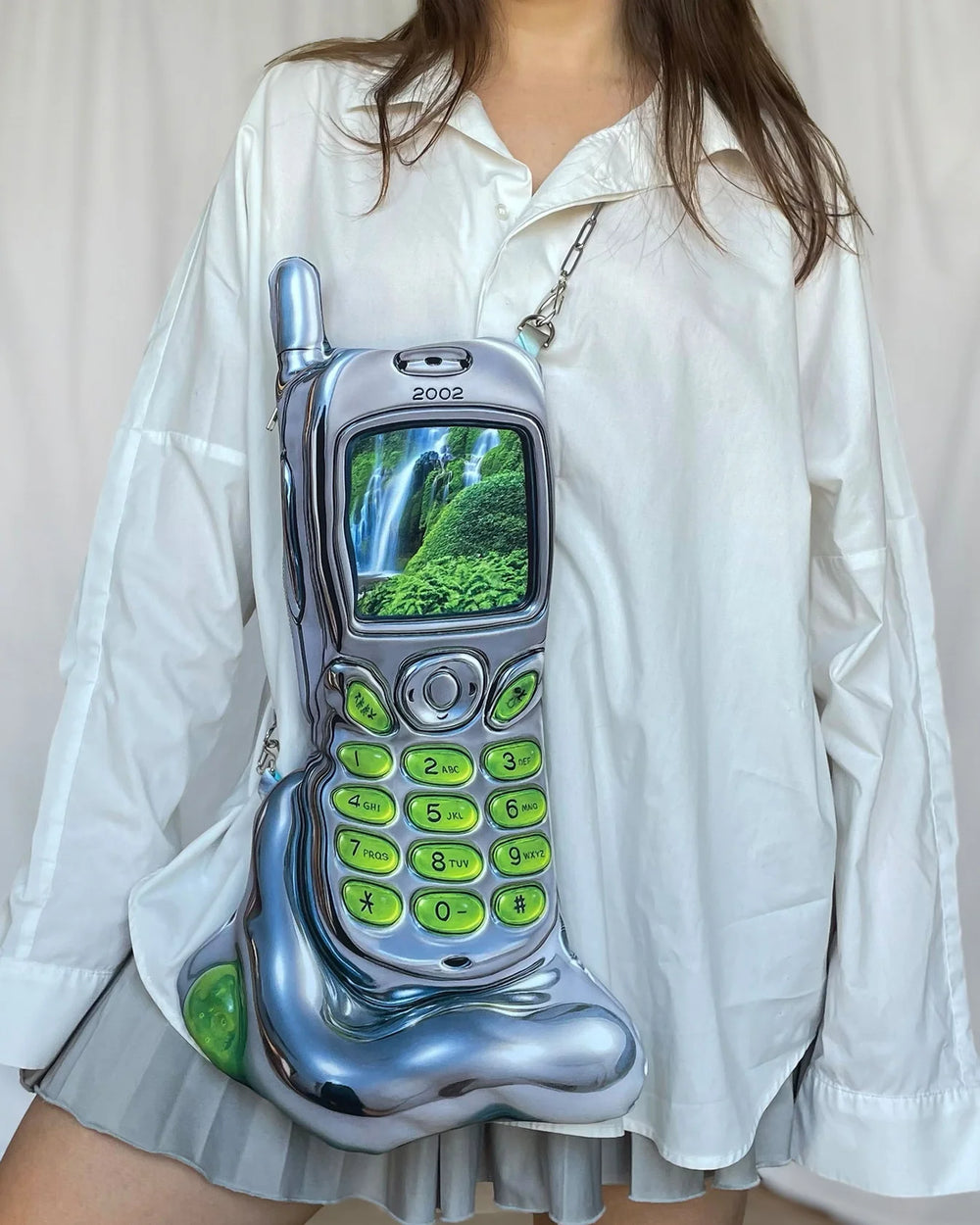 Vintage silver and green flip phone with a waterfall on the screen