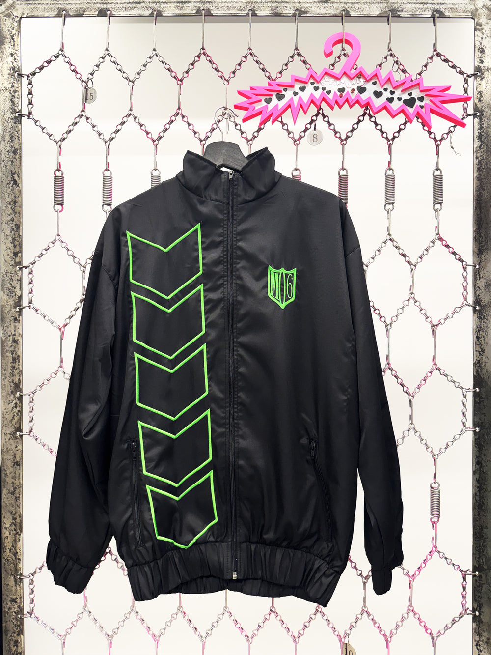 Black jacket with green designs on a hanger against a textured white background frontside 