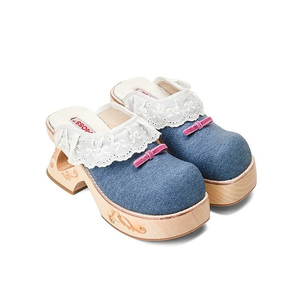 Pair of denim clogs with white lace and pink bows on a white background