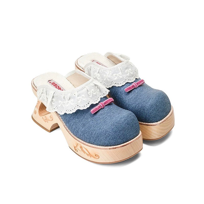 Pair of denim clogs with white lace and pink bows on a white background