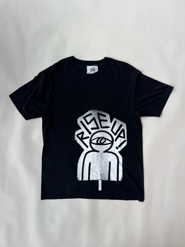 Unisex black cotton t-shirt featuring bold silver screen-printed graphic of abstract human figure with a single eye and the slogan ‘RISE UP!’ in graffiti-style font – edgy streetwear design ideal for urban fashion lovers and statement clothing fans