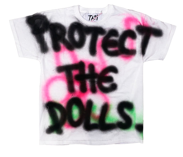 White t-shirt with spray-painted text 'PROTECT THE DOLLS' on a white background